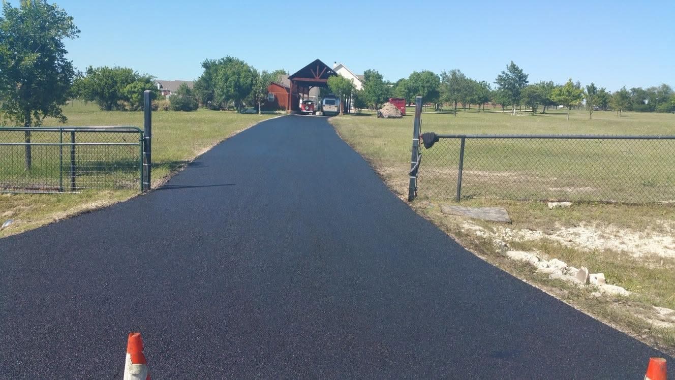 Finished asphalt driveway through a gated entrance