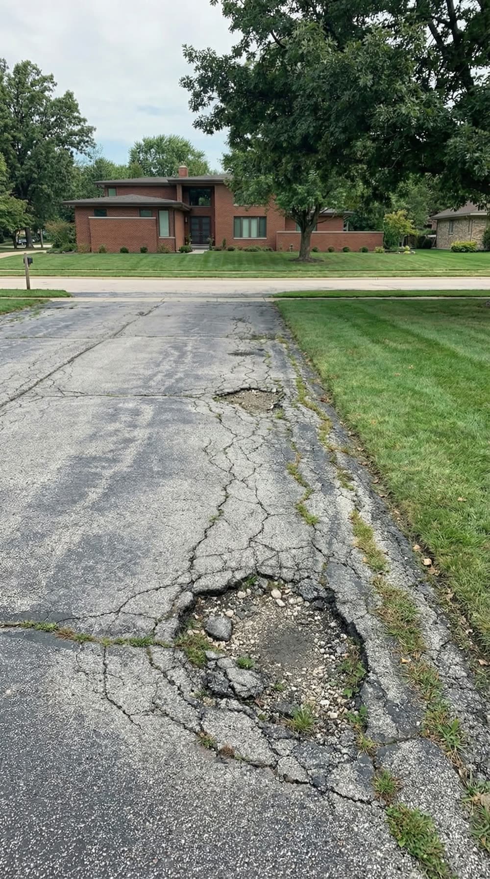 Cracked, worn-out asphalt driveway before Cornell's repaved it