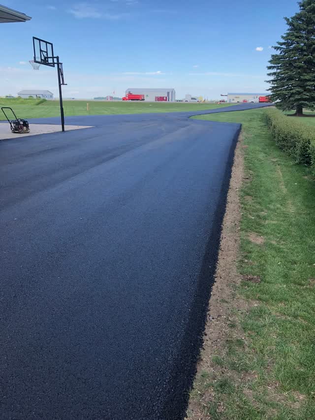 Wide asphalt pad with a basketball goal at a rural home