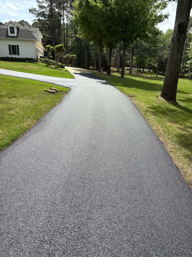 Long curving driveway to a white Cape Cod home
