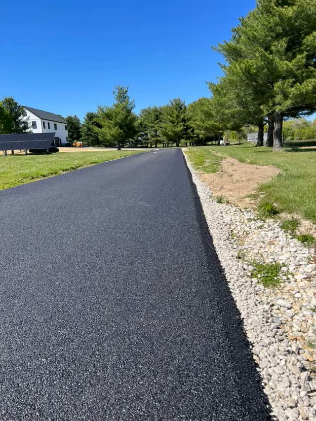 New country lane paved black past a farmhouse