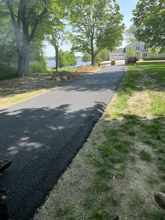 New asphalt driveway leading to a lakefront home