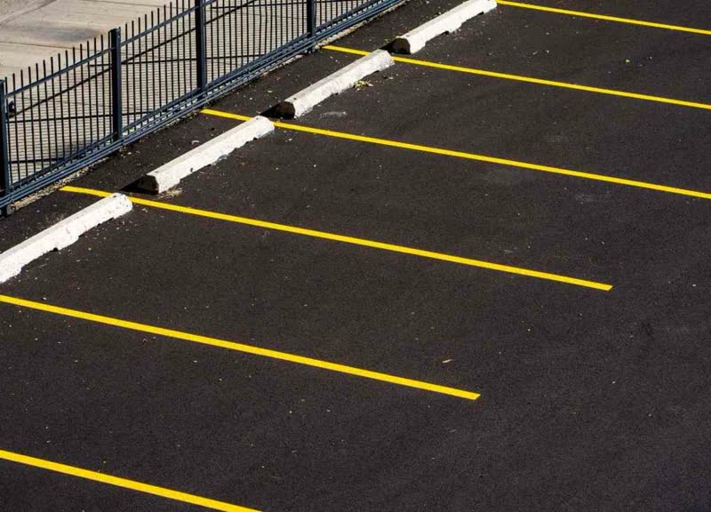 Crisp yellow parking stall stripes painted on dark asphalt